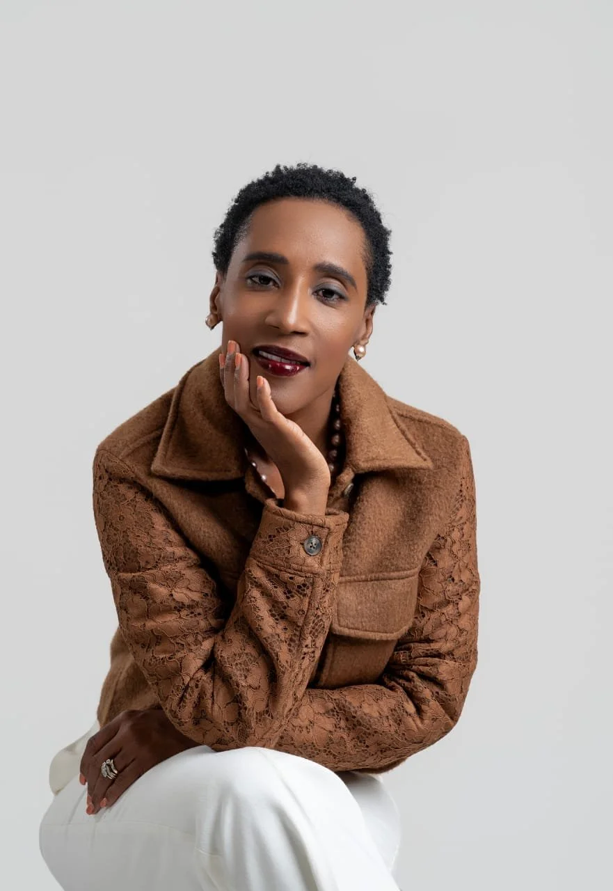 Portrait of Rolanda Desir Andre seated in a brown jacket
